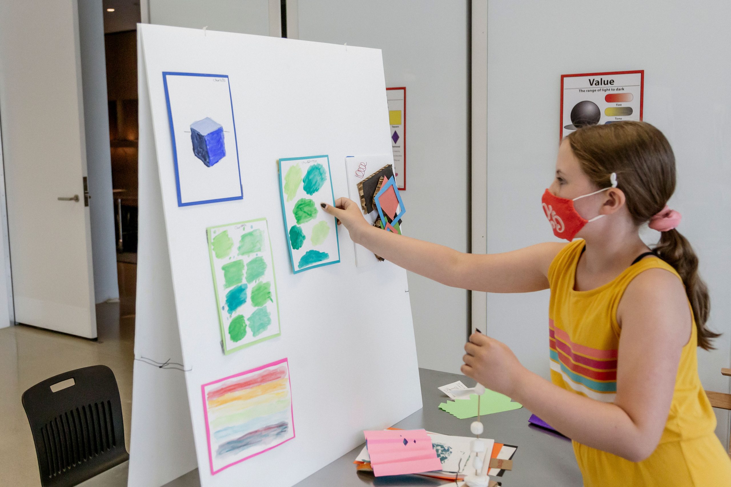 A child pins up art that they made at our Summer Art Camp.